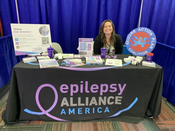 Amanda Mitchell sits at Epilepsy Alliance America booth at NASN 2024 conference in Chicago 