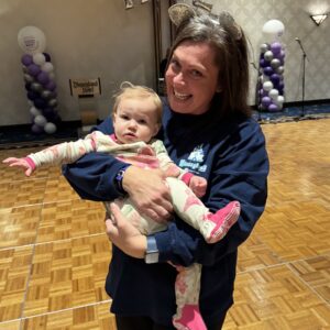 A woman holding a young girl in front of balloons that say Hope at the Epilepsy Awareness Day at Disneyland family dance party.